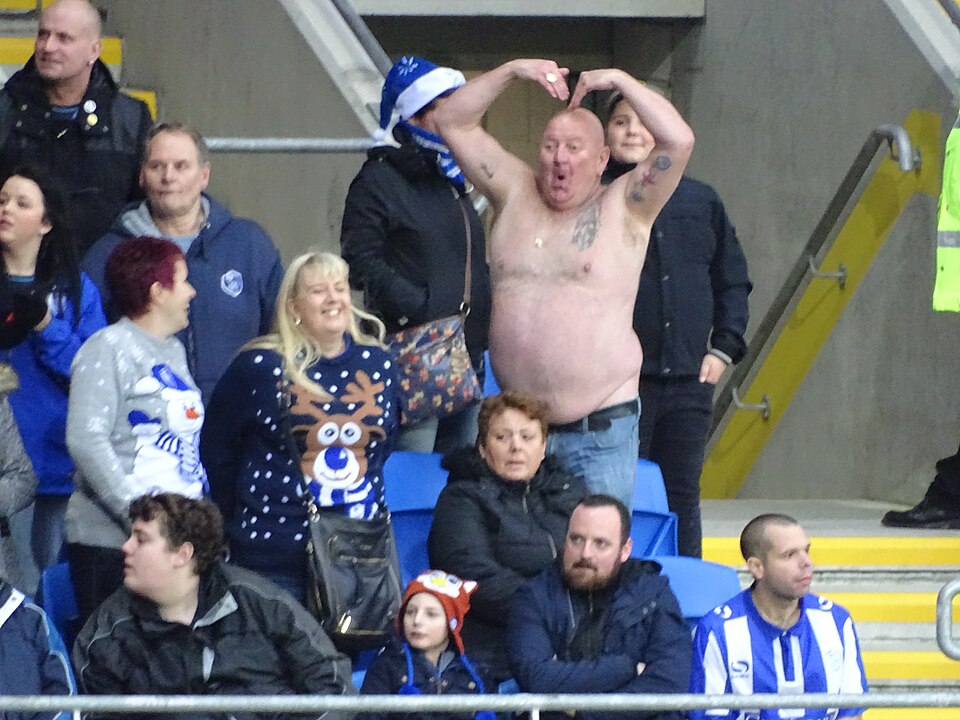 Aficionados viendo fútbol y cuotas en pantallas de un bar deportivo